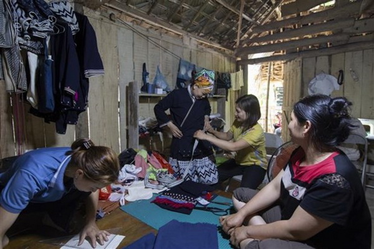 Du khách trải nghiệm mặc trang phục Dao Tiền khi đến du lịch tạn bản Sưng, xã Cao Sơn, huyện Đà Bắc (Hòa Bình). Ảnh: Trọng Đạt - TTXVN