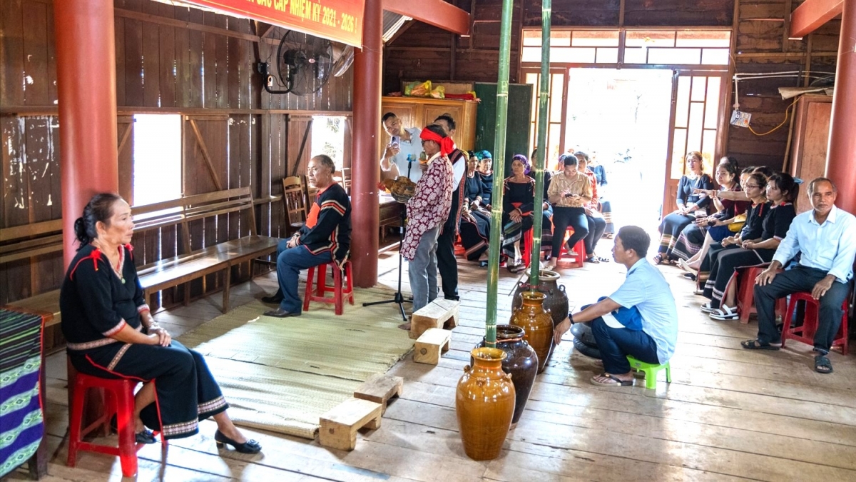 Thầy cúng ôm con gà đọc bài khấn trong nhà cộng đồng buôn