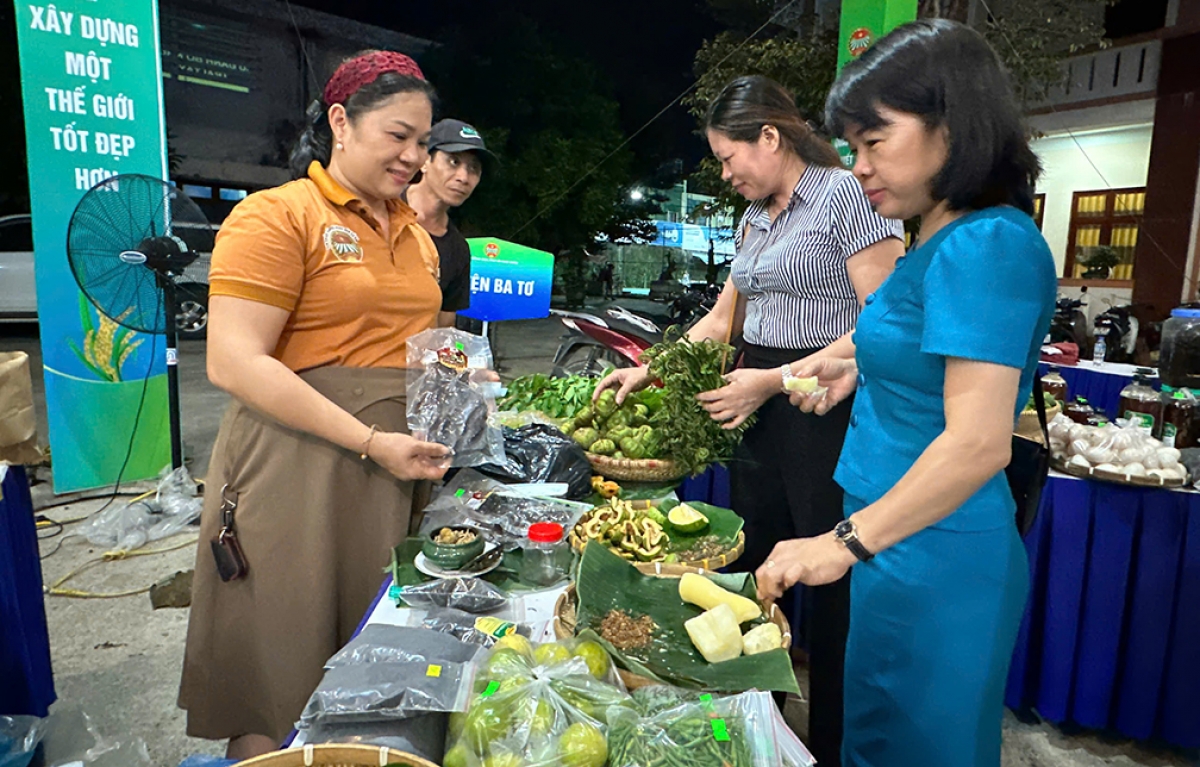 Bà Phan Thị Quyến, tiểu thương ở huyện miền núi Ba Tơ, tỉnh Quảng Ngãi (áo cam) đang giới thiệu đặc sản của Ba Tơ