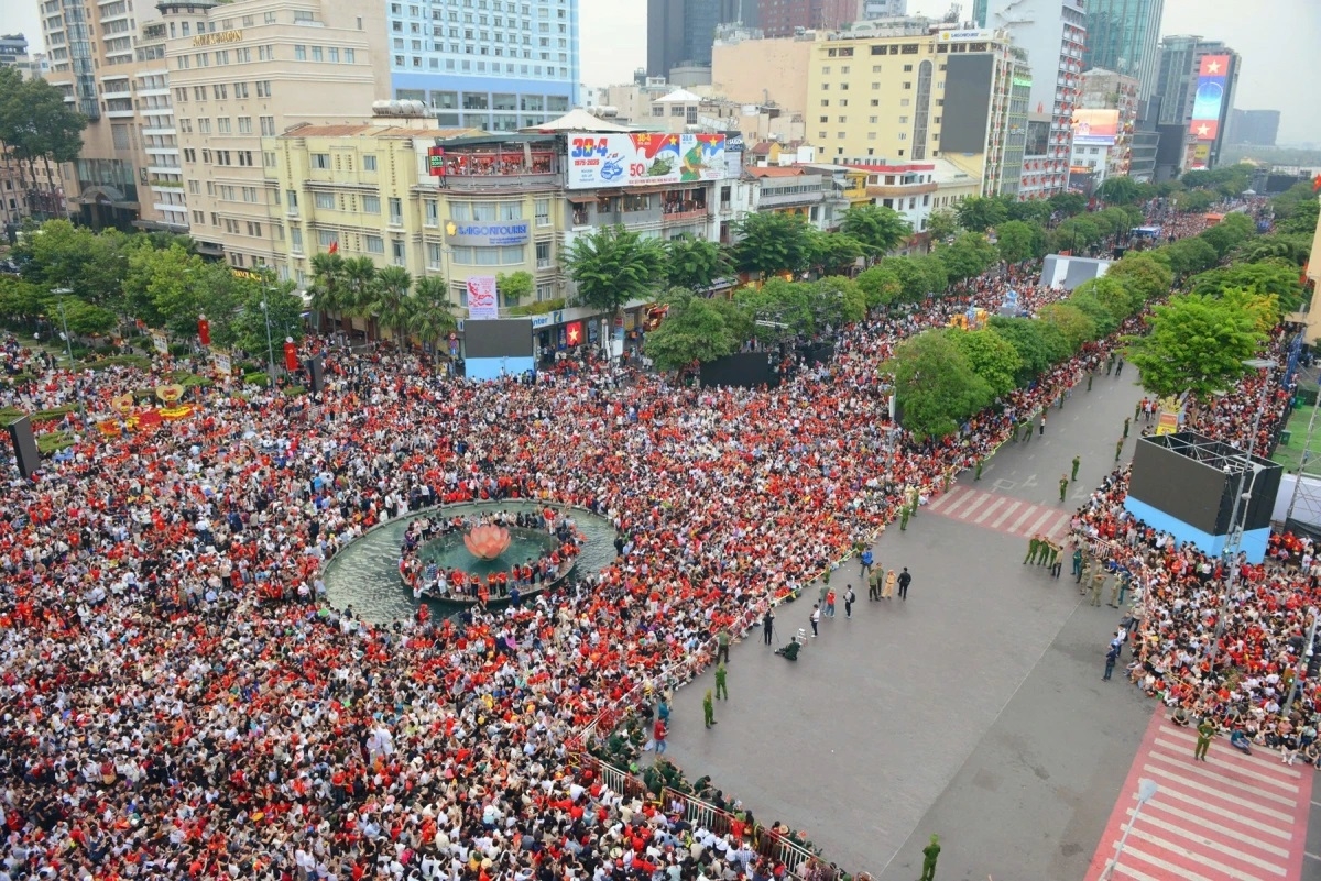 Biển người chờ đoàn diễu binh, diễu hành qua góc đường Nguyễn Huệ - Lê Lợi. Rất nhiều người mang trang phục màu đỏ, cầm cờ đỏ sao vàng thể hiện tinh thần tự hào dân tộc khi tham gia Lễ kỷ niệm 50 năm Ngày Giải phóng miền Nam, thống nhất đất nước (30/4/1975-30/4/2025).