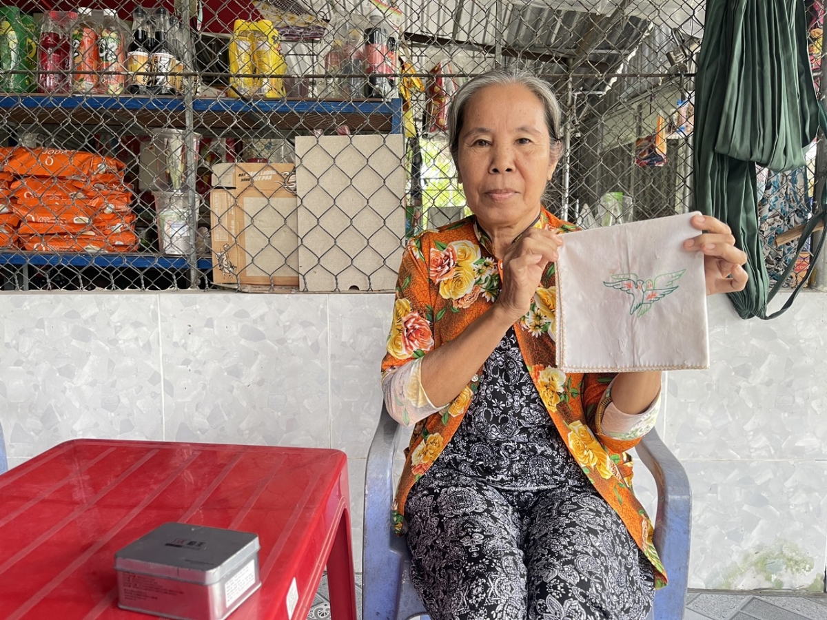 Bà Nguyễn Thị Me bên chiếc khăn thêu hình đôi chim bồ câu