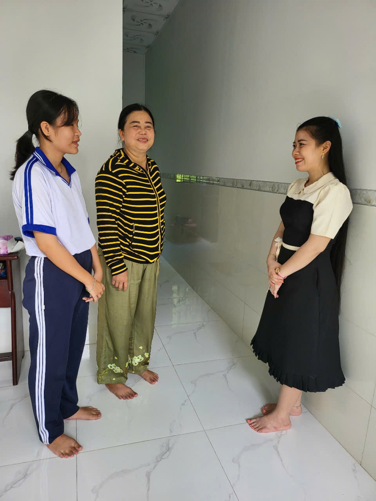 Em Phan Nguyễn Ngọc Nhi cùng mẹ (bên trái) với niềm vui trong căn nhà mới.