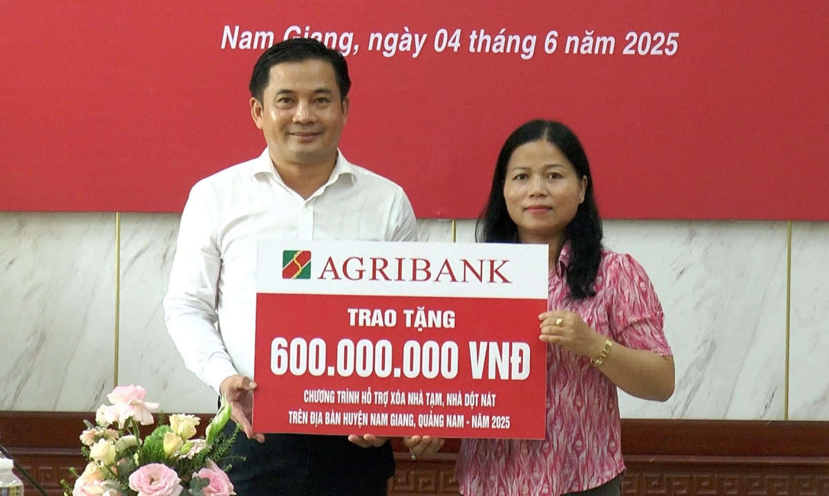 Lãnh đạo Agribank chi nhánh huyện Nam Giang (bên trái) trao tượng trưng kinh phí hỗ trợ xóa nhà tạm trên địa bàn huyện Nam Giang. Ảnh: Y THƠM