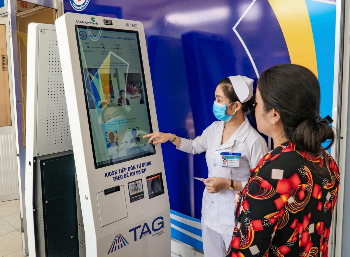 Nhân viên bệnh viện hướng dẫn người dân đăng ký khám bệnh tại ki-ốt thông minh