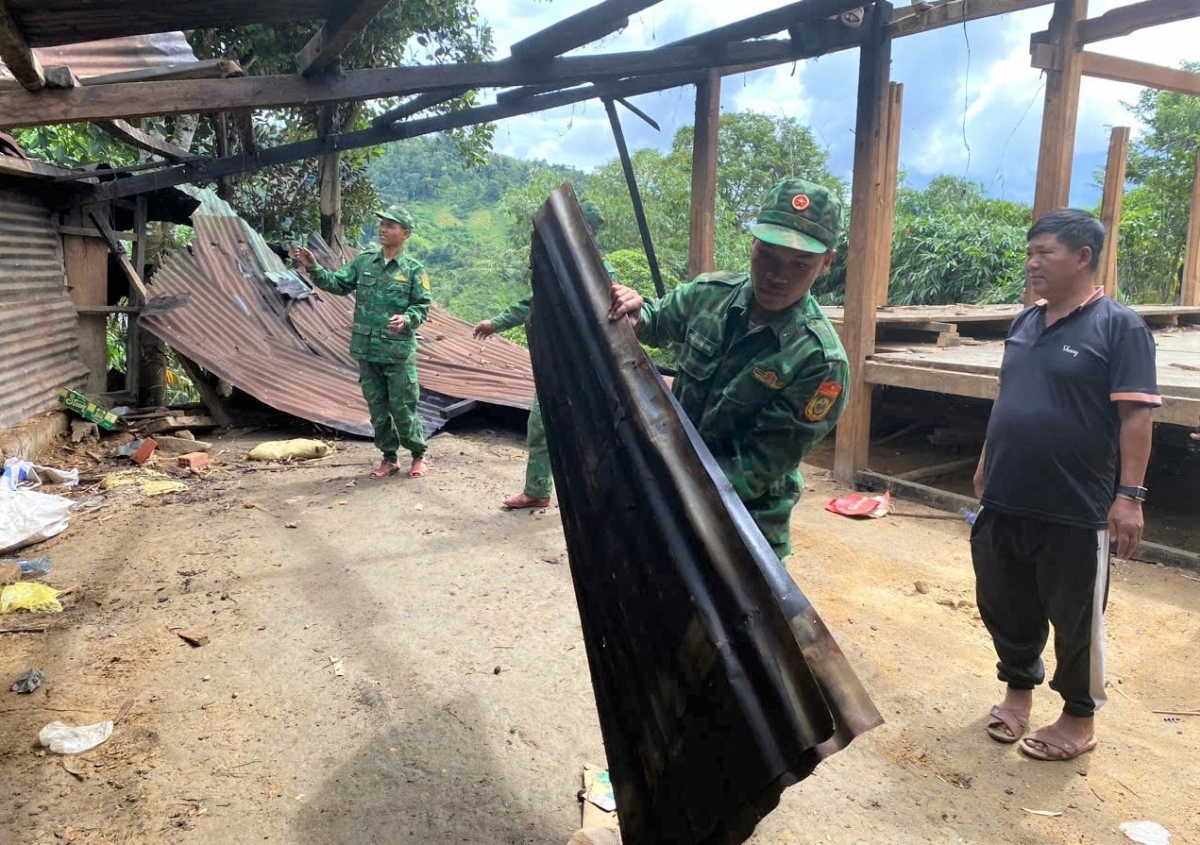 Lực lượng biên phòng di chuyển mái tôn khỏi vị trí sạt lở. Ảnh: ĐĂNG NGUYÊN