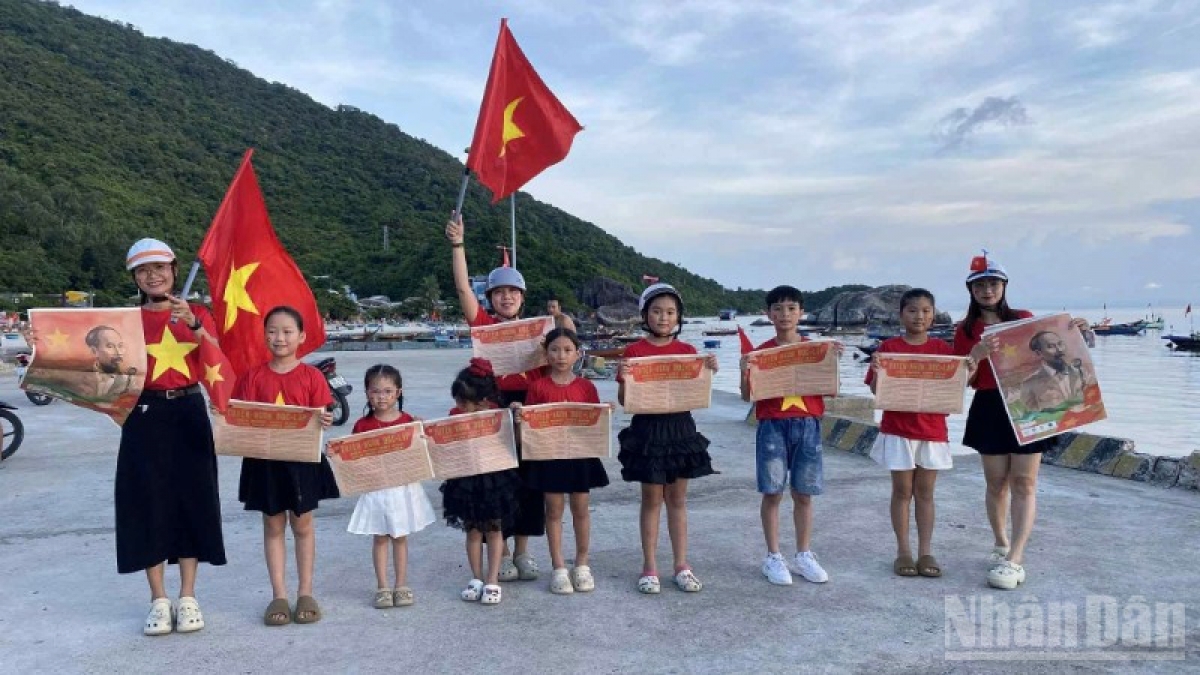 Du khách tham quan đảo Cù Lao Chàm, thành phố Đà Nẵng và ghi lại hình ảnh đáng nhớ với ấn phẩm phụ san đặc biệt kỷ niệm 80 năm Quốc khánh của Báo Nhân Dân trao tặng. (Ảnh: TÙNG LÂM)