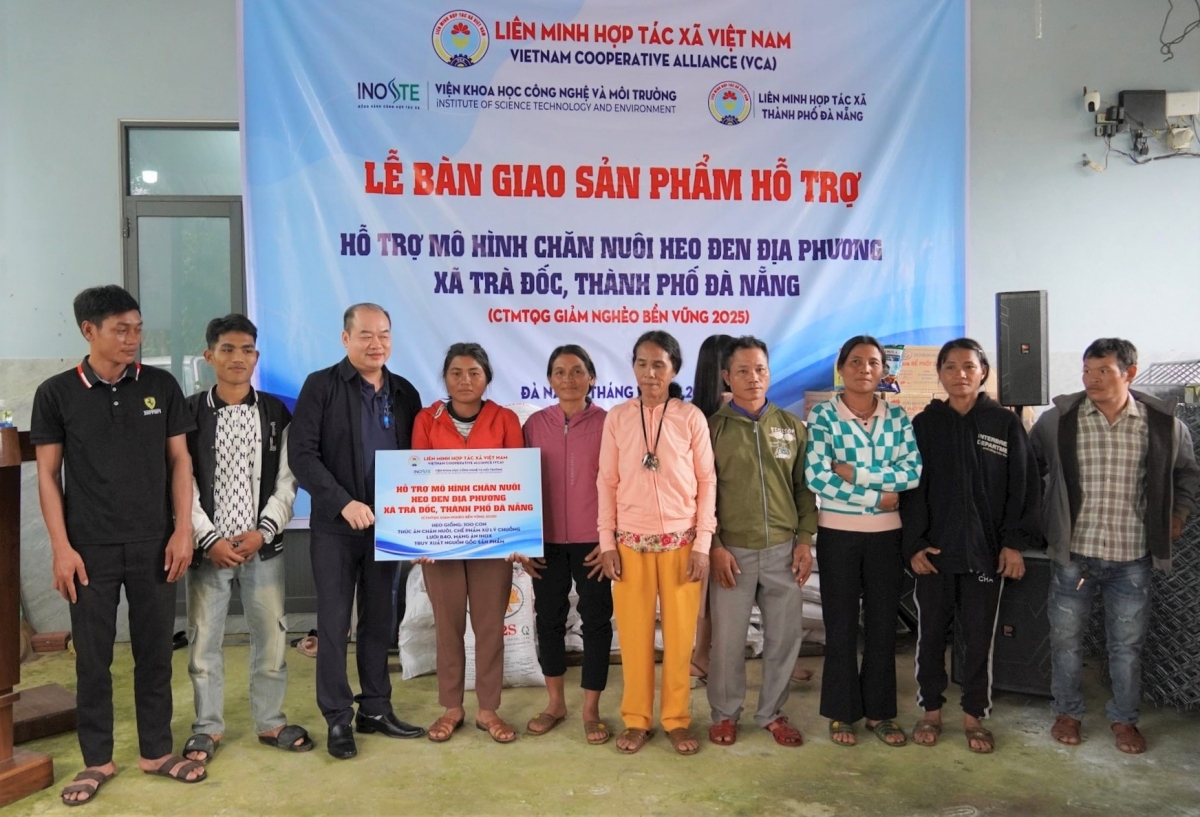 Đại diện dự án trao biển tượng trưng hỗ trợ mô hình chăn nuôi heo đen địa phương cho các hộ dân xã Trà Đốc. Ảnh: THANH KHIẾT