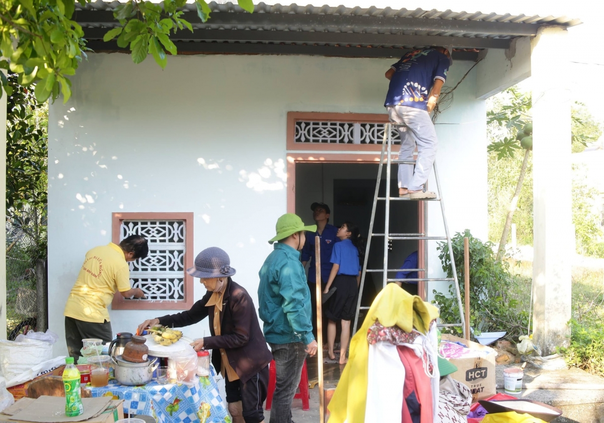 Đoàn viên thanh niên xã Tam Anh sơn sửa nhà cho bà Ôn Thị Nghĩa, cựu thanh niên xung phong. Ảnh: LAM PHƯƠNG