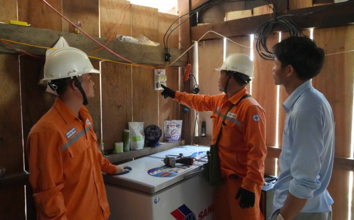 Cán bộ điện lực hướng dẫn người dân cụm dân cư 3B làm quen với cách sử dụng điện.