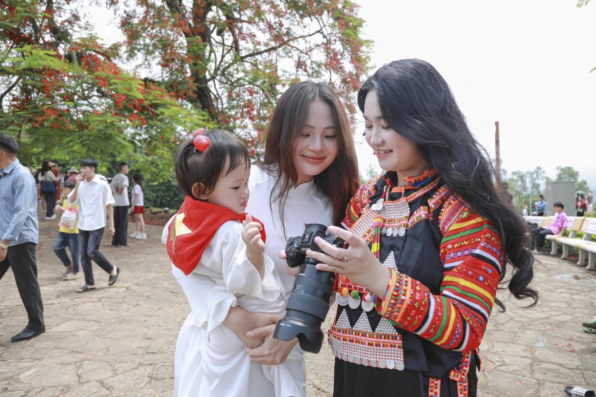 Dịp này, chúng ta cũng dễ dàng bắt gặp hình ảnh những em nhỏ khoác lên mình cờ đỏ sao vàng chụp ảnh dưới tán phượng rực nở ...