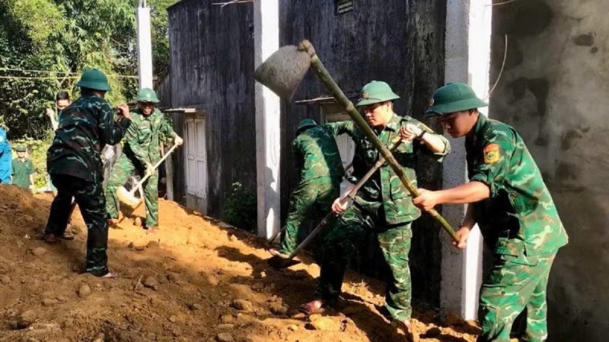Cán bộ, chiến sĩ Đồn Biên phòng Vinh Hiền hỗ trợ san lấp nền nhà cho gia đình bà Lê Thị Chắt.
