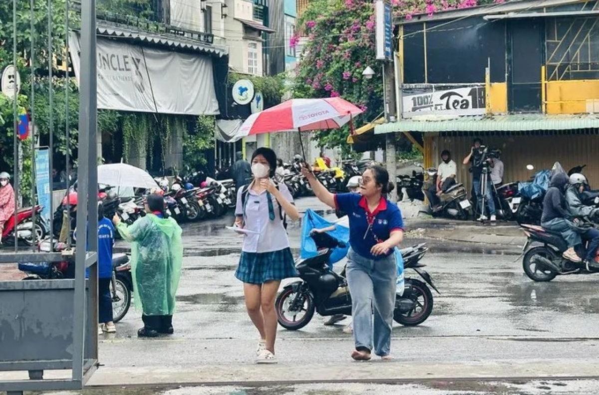Lực lượng tình nguyện viên hỗ trợ thí sinh di chuyển vào điểm thi THPT Gia Định. Ảnh: THU TÂM