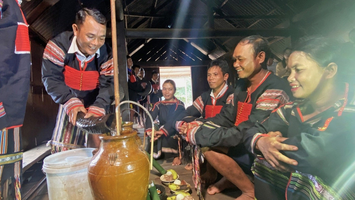 Nghi thức uống rượu cần trong Lễ kết nghĩa anh em của người M’nông: Người đàn ông dùng sừng trâu múc nước lọc rót vào ché rượu cần lớn. Ảnh: Báo Đắk Lắk. 