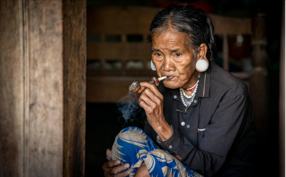 Người già vẫn giữ tục căng tai và hút thuốc bằng tẩu - Ảnh: Thành Đạt.