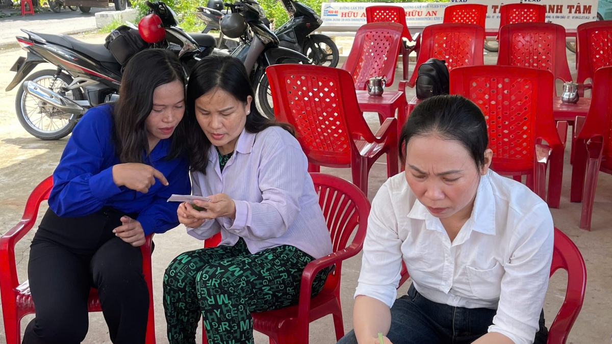 Chị Thạch Thị Dân, Trưởng Ban Nhân dân khu vực No Tom (áo xanh) đang hướng dẫn người dân về chuyển đổi số trên điện thoại thông minh. Ảnh: Thạch Hồng-CTV Sê Rây/VOV ĐBSCL