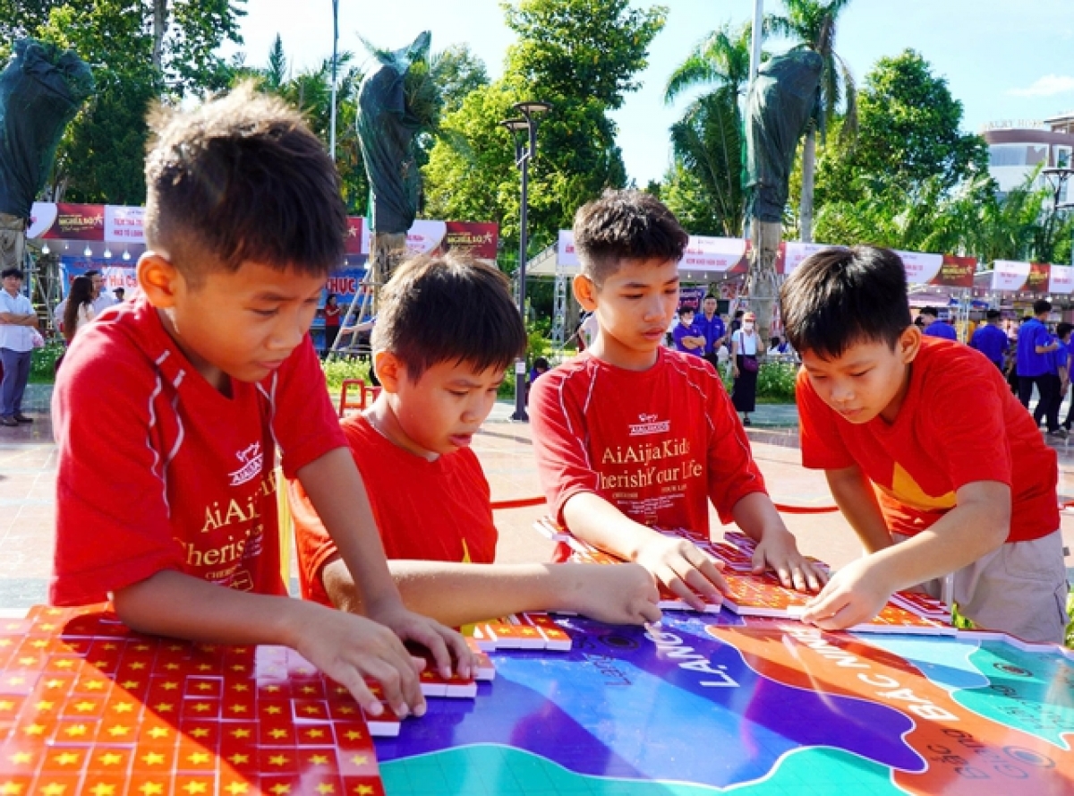 Nhiều em nhỏ tham gia lắp ghép mô hình bản đồ Việt Nam bằng những lá cờ