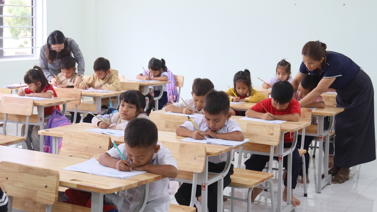 Giáo viên Trường Phổ thông nội trú liên cấp Tiểu học – Trung học cơ sở xã Rờ Kơi hướng dẫn học sinh viết chữ cái Tiếng Việt. Ảnh: Thanh Thắng/VOV Miền Trung.