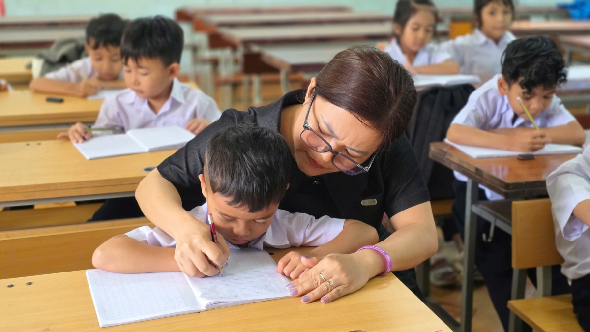 Giáo viên kèm học sinh tập viết tại lớp