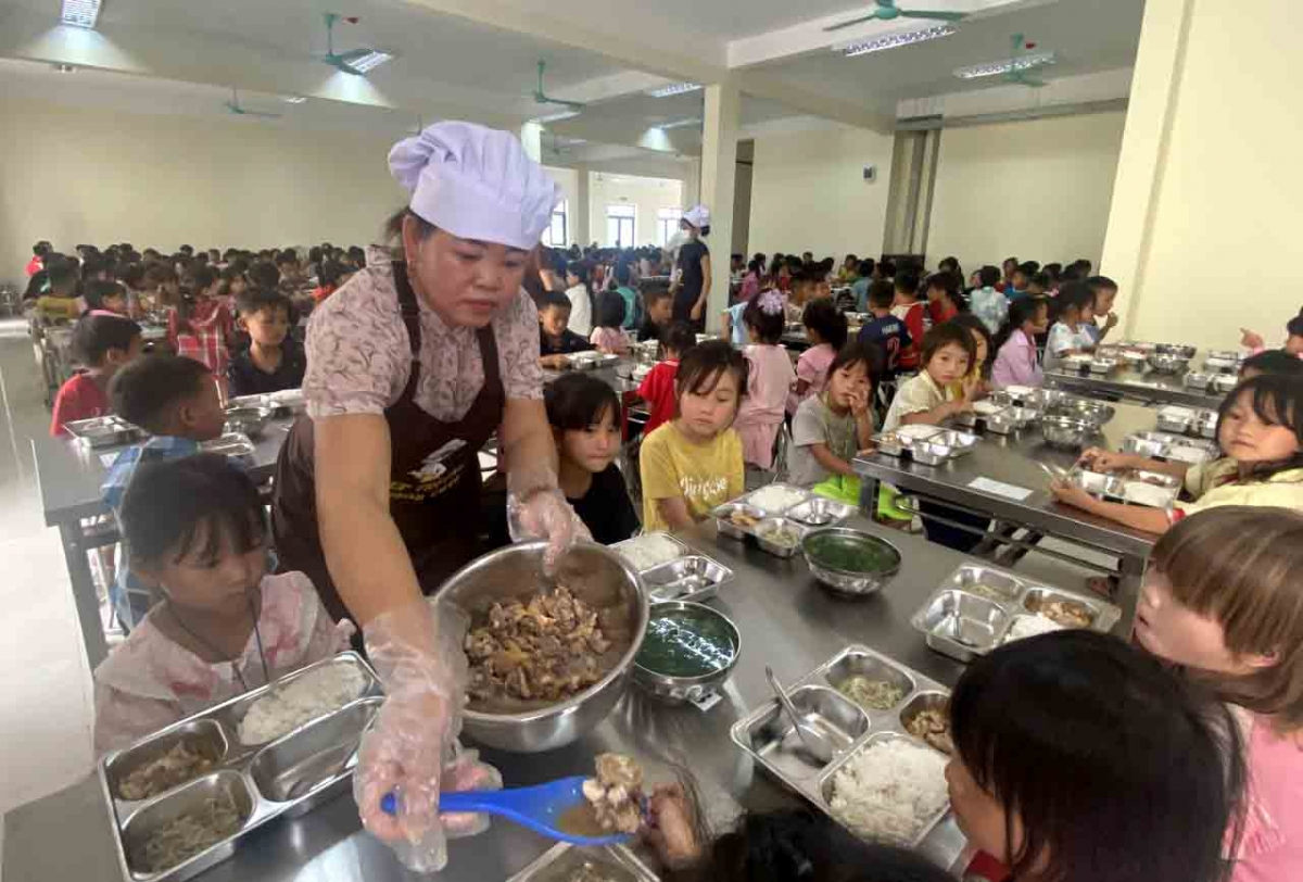 Chị Lù Thị Hưởng, nhân viên nhà bếp trường liên cấp Pa Tần chia thêm khẩu phần ăn cho học sinh (Ảnh: Khắc Kiên)