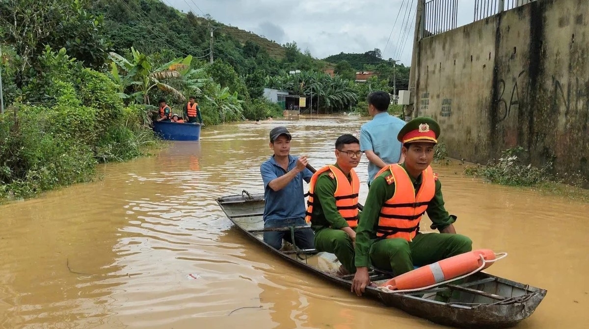 Lực lượng Công an xã Tà Đùng dùng xuồng hỗ trợ người dân di chuyển qua khu vực ngập sâu (Ảnh: Quang Sáng)