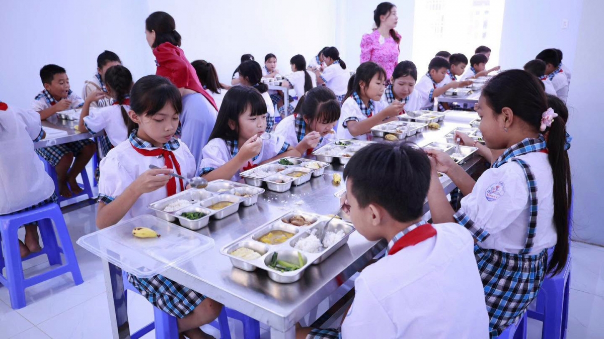 Lần đầu ăn tập trung, nhiều em còn bở ngỡ nên được giáo viên hướng dẫn (Ảnh: Thiên Lý)