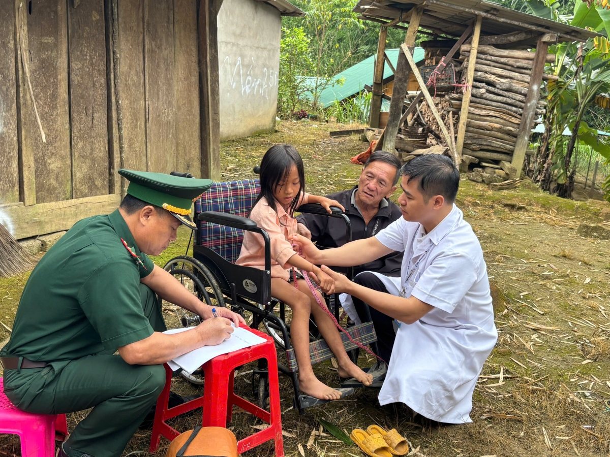 Thạc sĩ, bác sĩ Nguyễn Đình Hưng, Giám đốc Tổ chức Helping Vietnam Children (áo blouse trắng) trực tiếp thăm khám tại nhà cho Lầu Y Ồng. Ảnh: Thiên Bình.