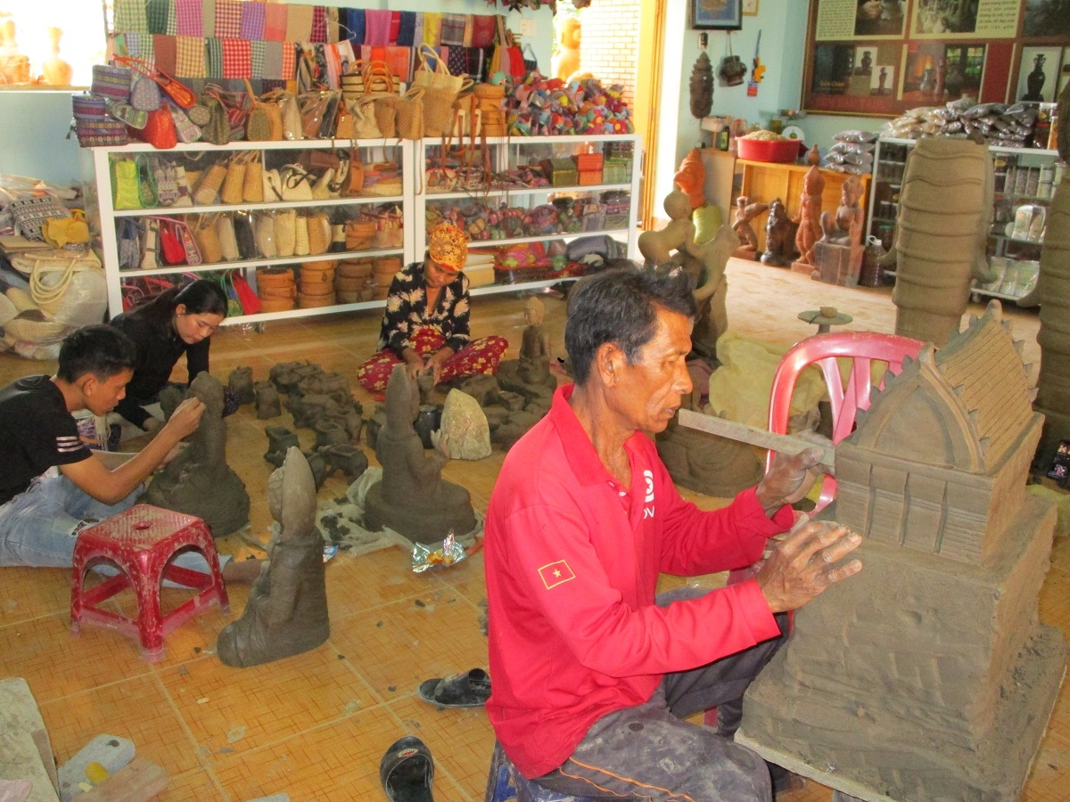 Nghệ nhân (áo đỏ) đang tạo hình tháp Chăm bằng gốm (Ảnh: Đoàn Sĩ)