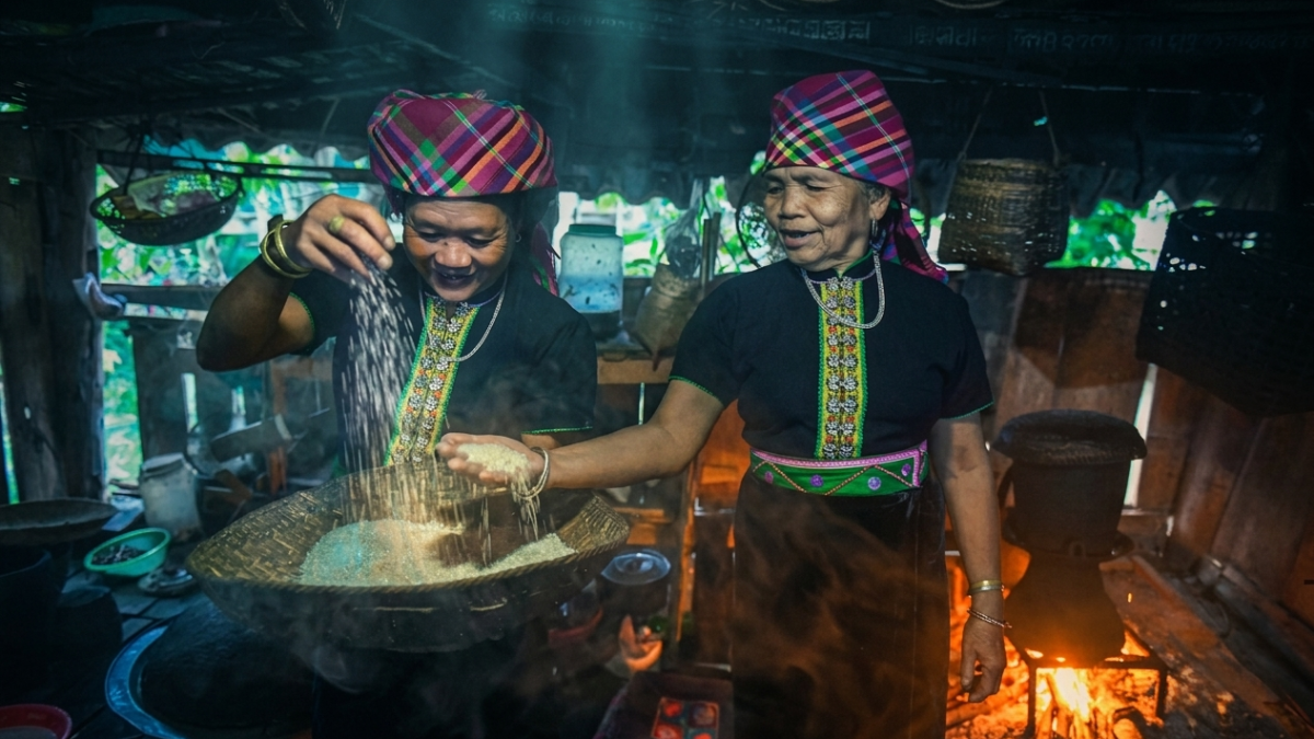 Những người phụ nữ Khơ Mú đang chuẩn bị gạo bên ánh lửa bập bùng. Dù là không gian bếp sinh hoạt hàng ngày, nơi đây vẫn luôn mang một vẻ tĩnh mịch, huyền bí và gắn liền với đời sống tâm linh sâu sắc của đồng bào. Ảnh: Thành Đạt.