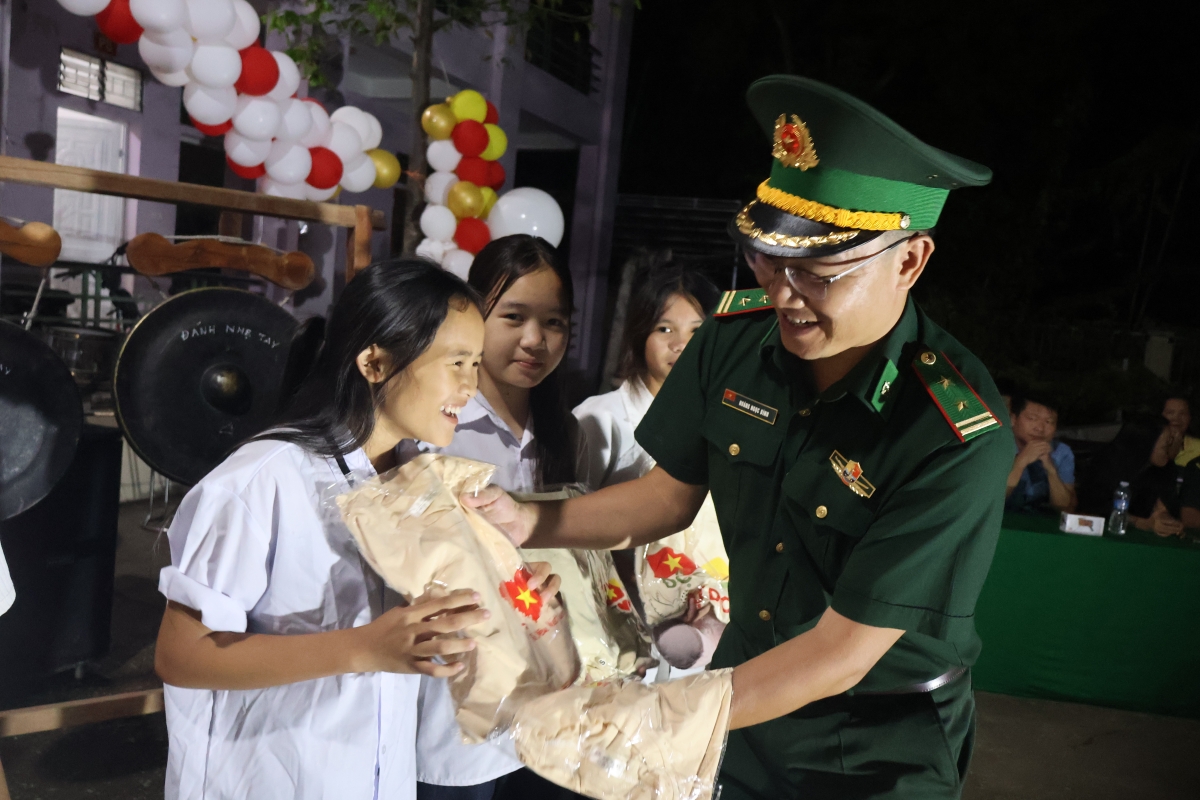 Trung tá Hoàng Ngọc Bình- Chính trị viên Đồn Biên phòng Môn Sơn trao những món quà của BTC tới các em nhỏ dân tộc Đan Lai (Ảnh: Tuấn Anh)