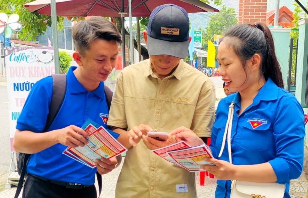 Đoàn viên thanh niên hướng dẫn người dân quét mã QR
thanh toán không dùng tiền mặt (Ảnh: Vinh Thông)